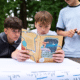 Das Editorial-Bild zeigt drei Schüler beim Testen eines Materials des Rucksack voll Meer. Hier begutachten sie das Buch Wir Menschen und das Meer.